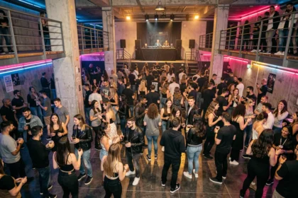Ambiance générale d'une boîte de nuit en Seine-Saint-Denis avec une foule diverse dansant dans un espace industriel chic