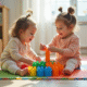 Deux jeunes filles de 3 ans jouent avec des blocs sur un tapis coloré